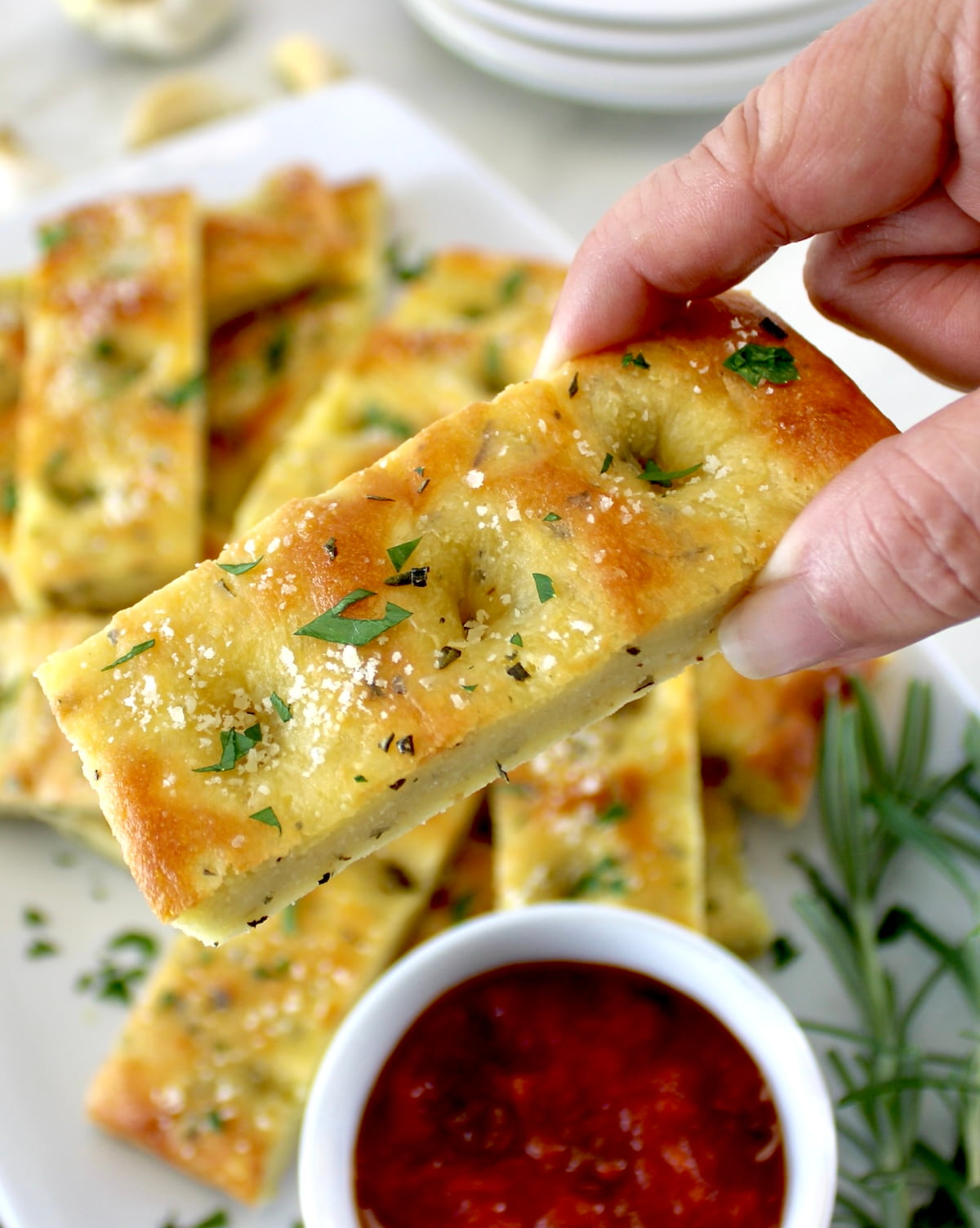 holding up Keto Focaccia Breadstick with marinara sauce in cup