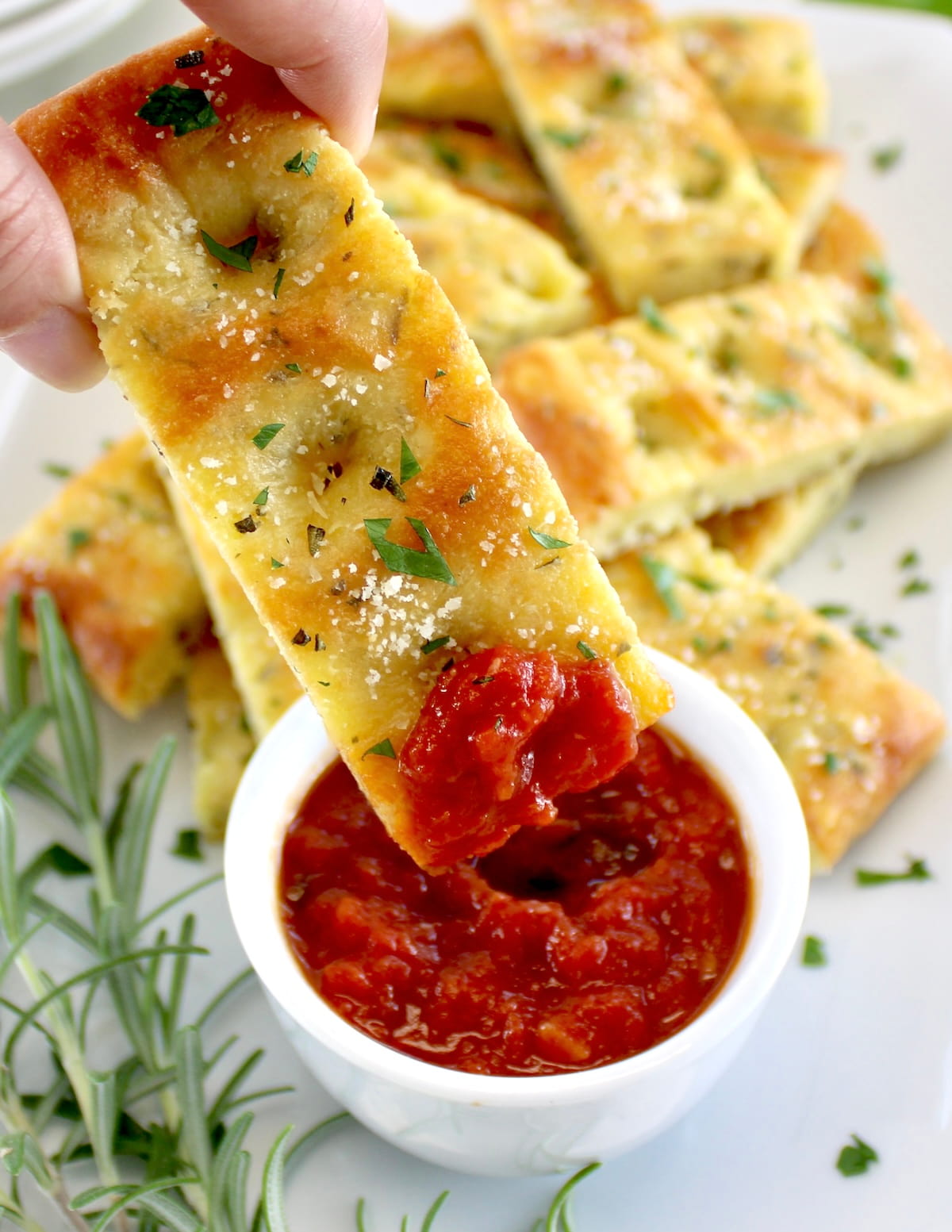 holding Keto Focaccia Breadstick dipped in marinara sauce