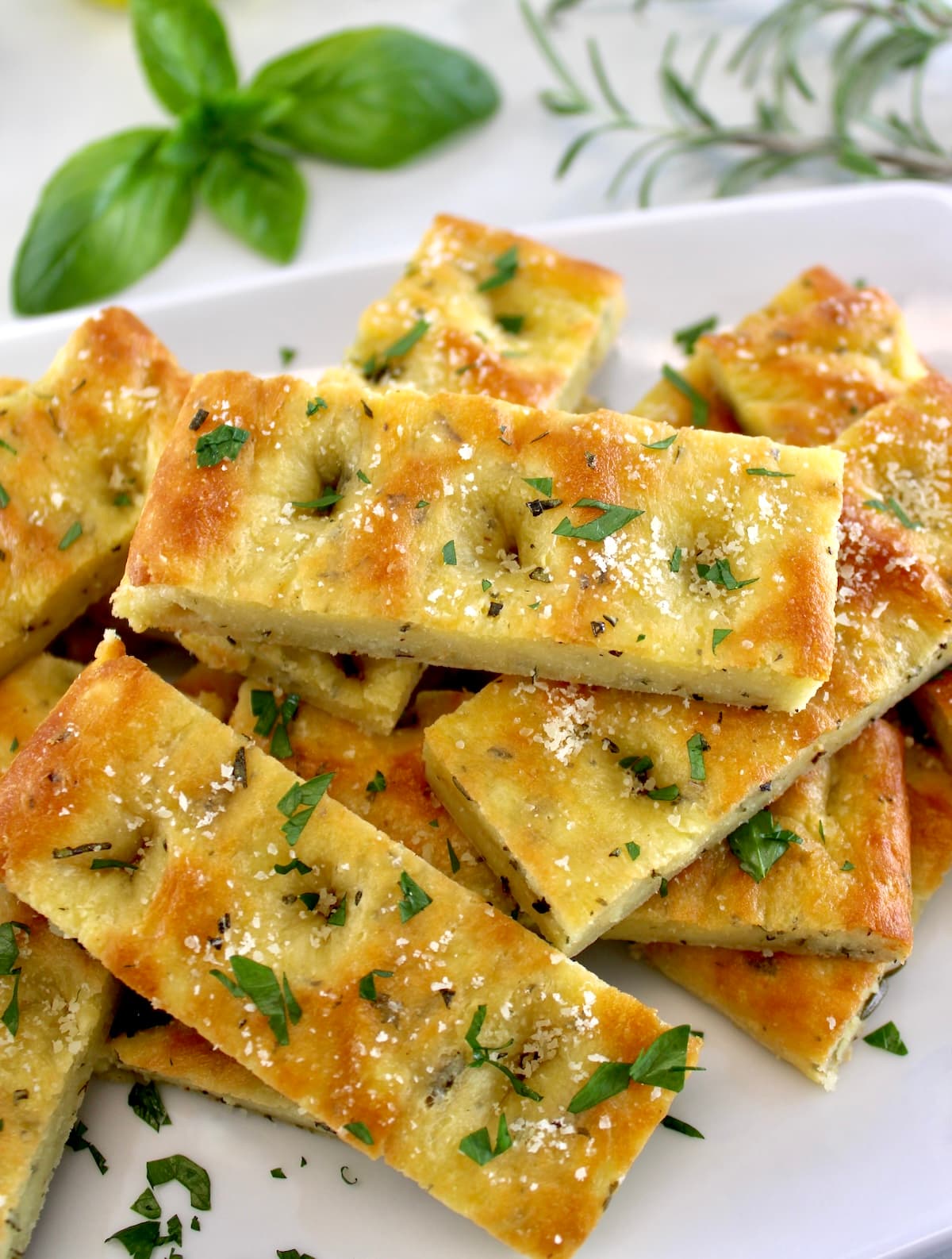 closeup of Keto Focaccia Breadsticks stacked up on white plate