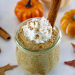 Pumpkin Chia Pudding in open jar with whip cream and cinnamon stick on top