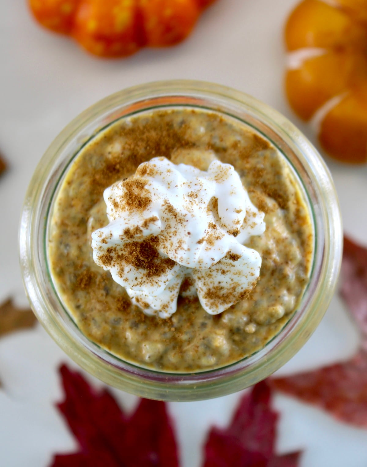 overhead closeup of Pumpkin Chia Pudding in open glass jar with whip cream on top