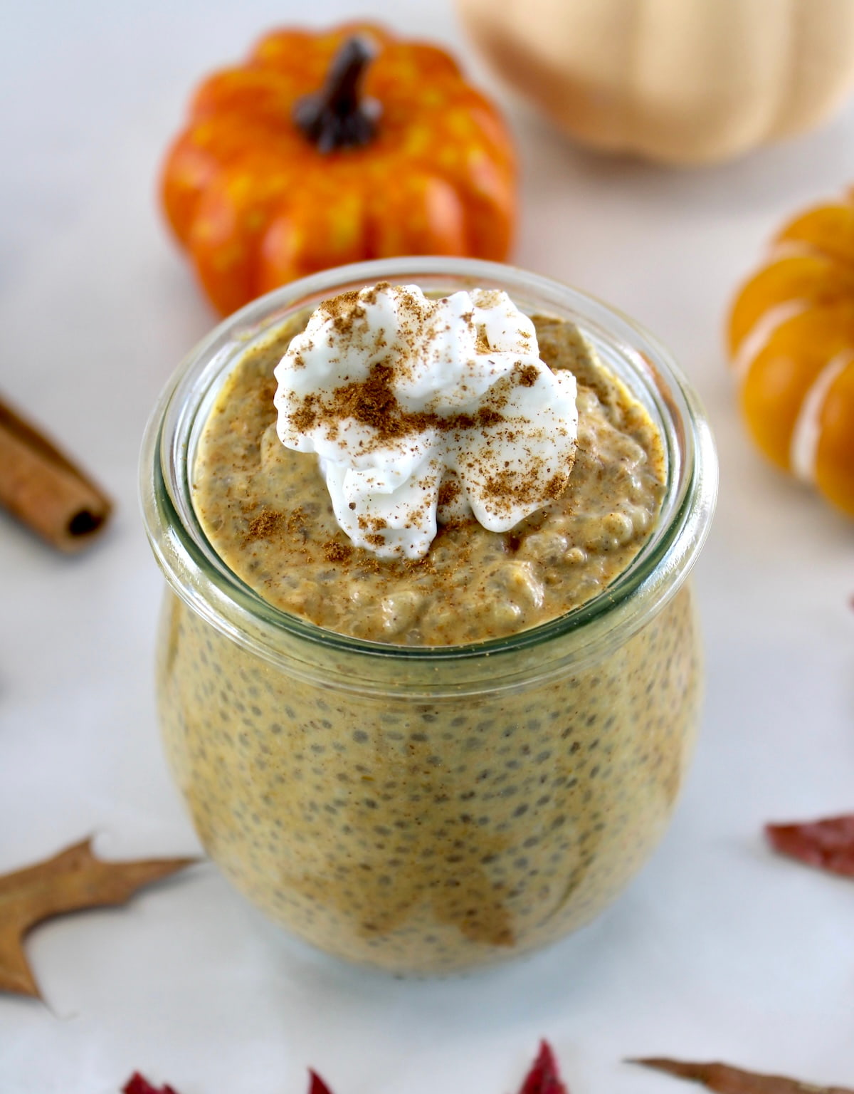 overhead view of Pumpkin Chia Pudding in open glass jar with whip cream on top