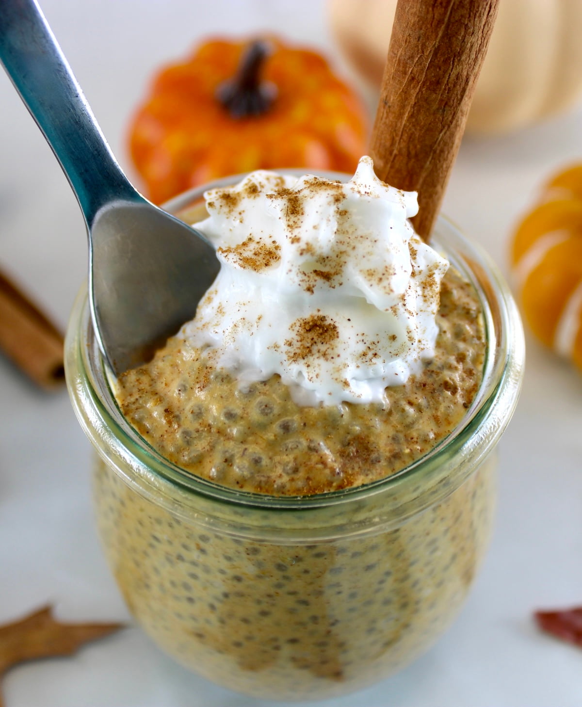 Pumpkin Chia Pudding with whip cream and cinnamon stick on top and spoon on side