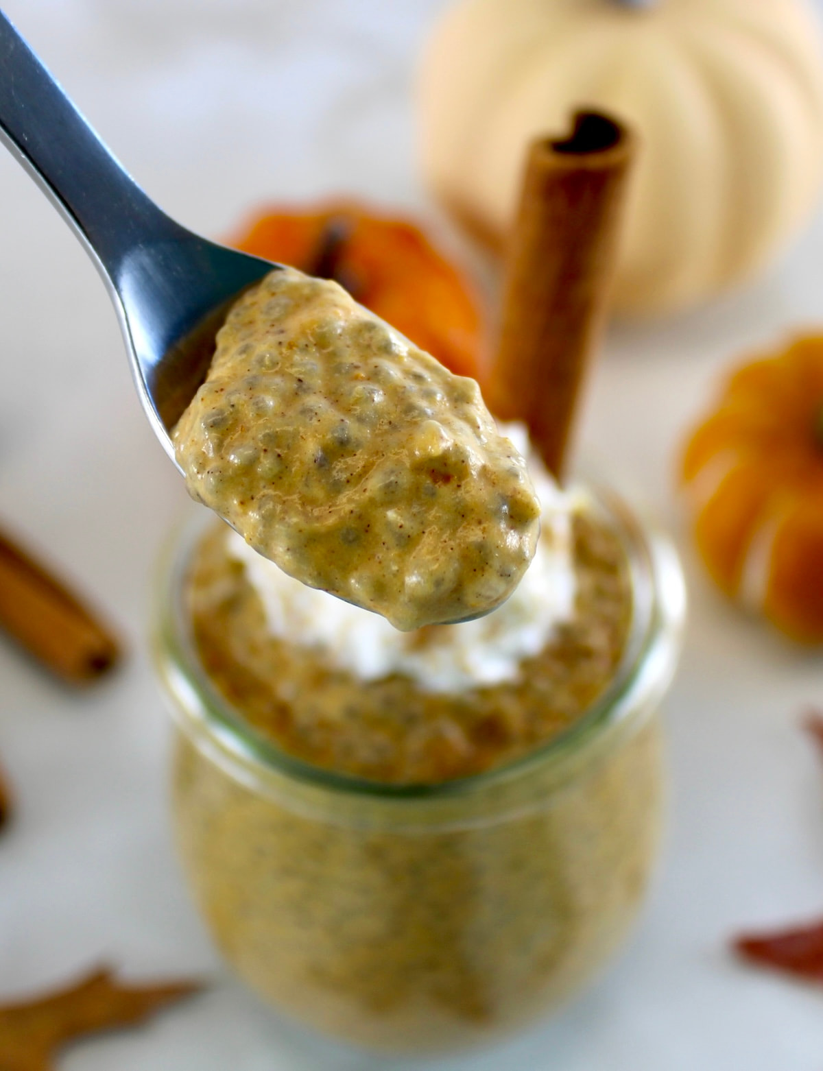 holding up spoonful of Pumpkin Chia Pudding over open glass jar