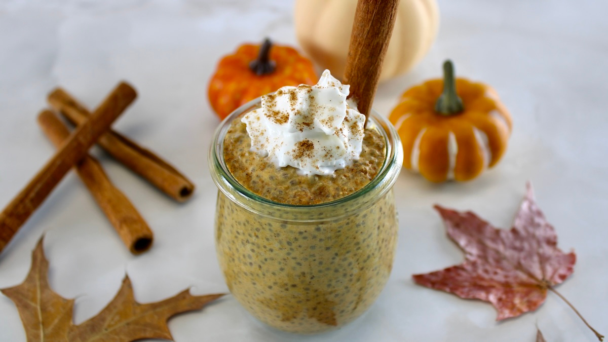 Pumpkin Chia Pudding in glass jar with whip cream and cinnamon stick on top