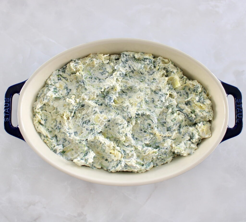 overhead view of Spinach Artichoke Dip in oval casserole unbaked