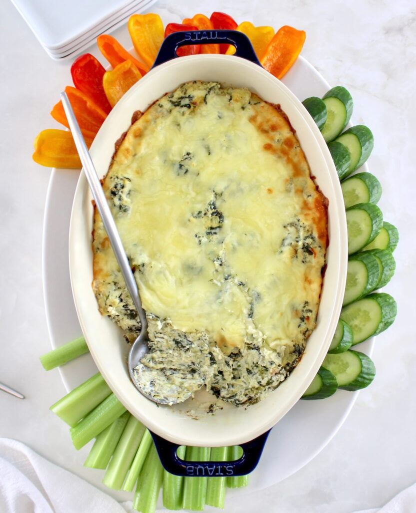 overhead view of Spinach Artichoke Dip in oval casserole with serving spoon on side