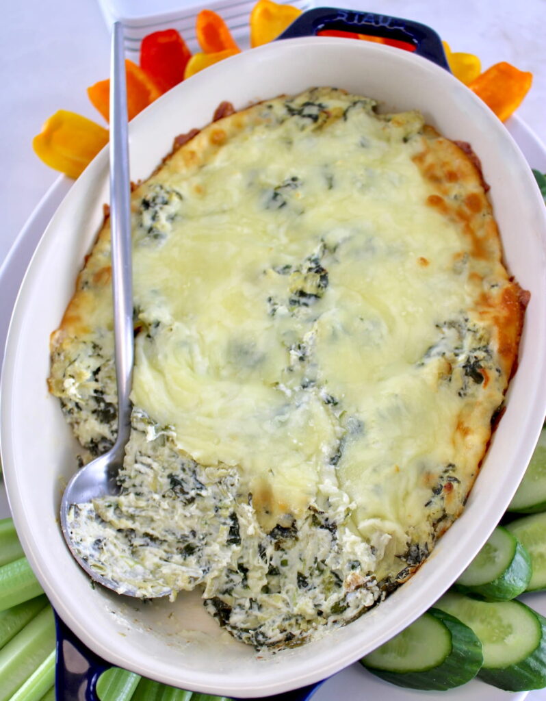 overhead view of Spinach Artichoke Dip in casserole dish with serving spoon on side