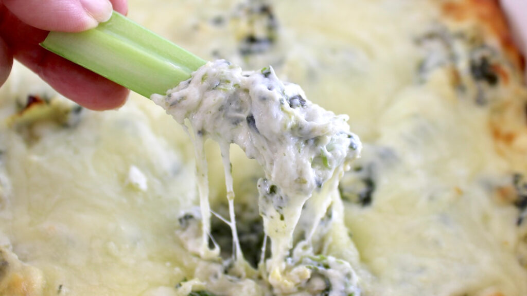 celery stick dipped in Spinach Artichoke Dip