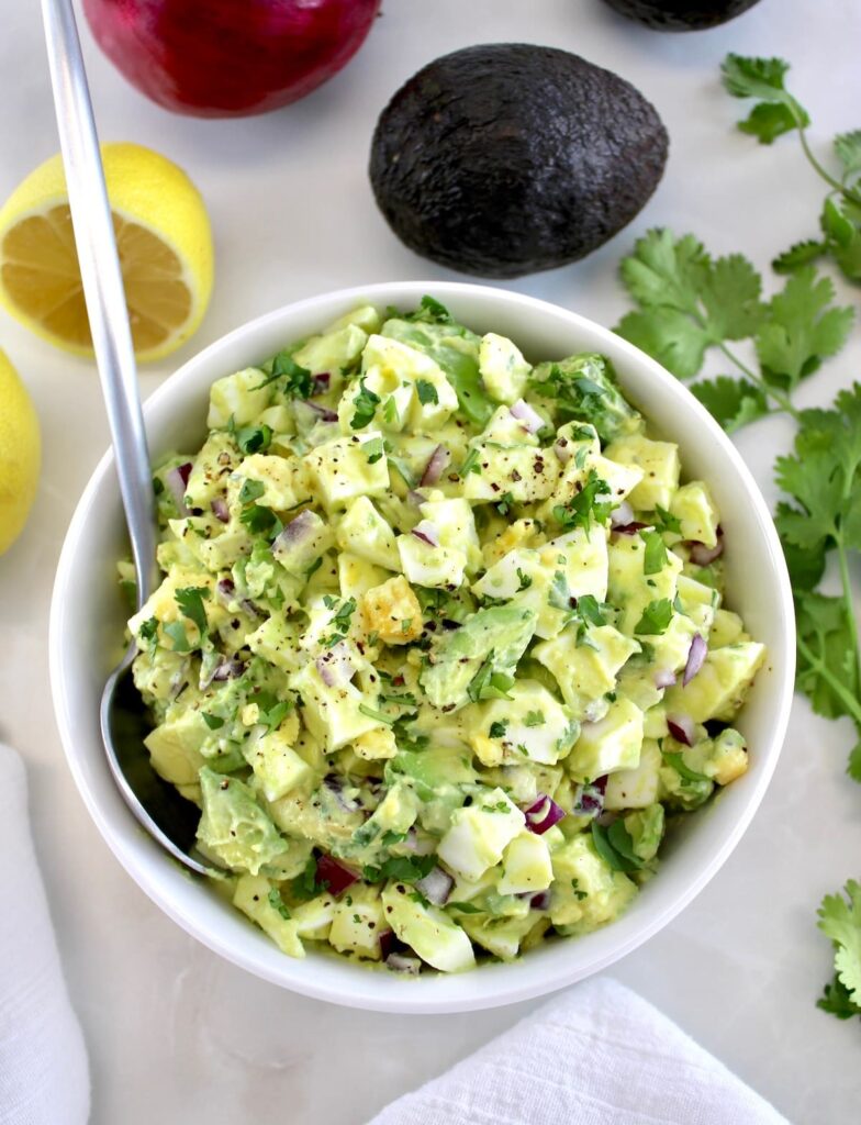 Avocado Egg Salad in white bowl with spoon on side