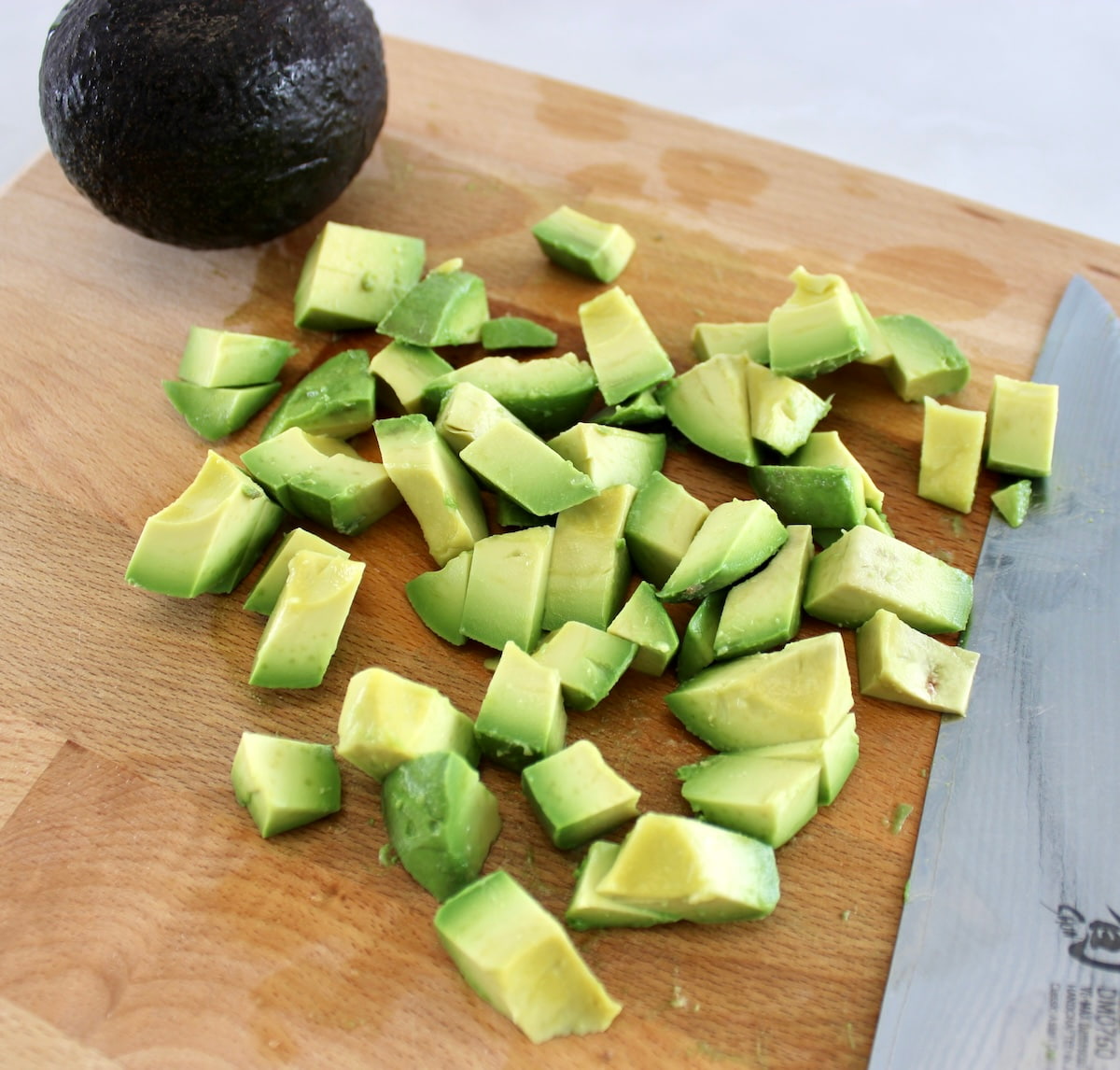 chopped avocado on cutting board with knife