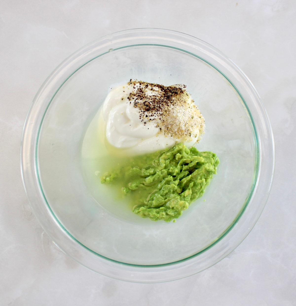 Avocado Egg Salad dressing ingredients in glass bowl unmixed