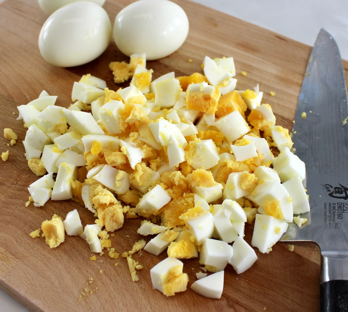 chopped hard boiled eggs on cutting board with knife