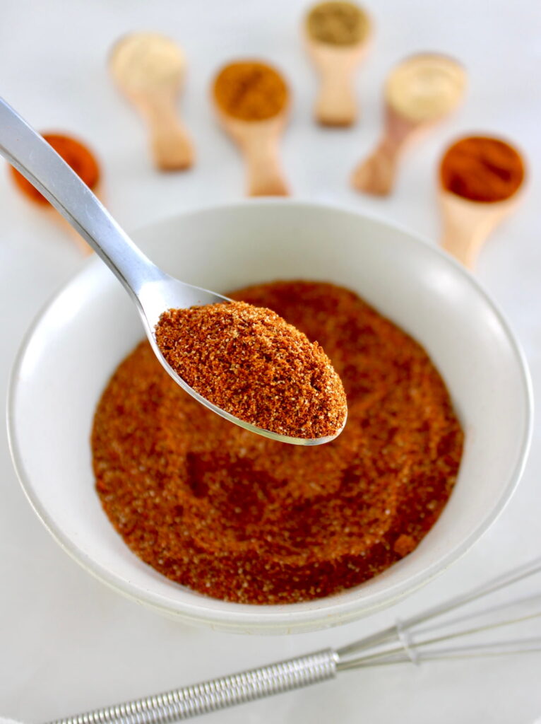 Homemade Chili Seasoning in spoon held up over white bowl