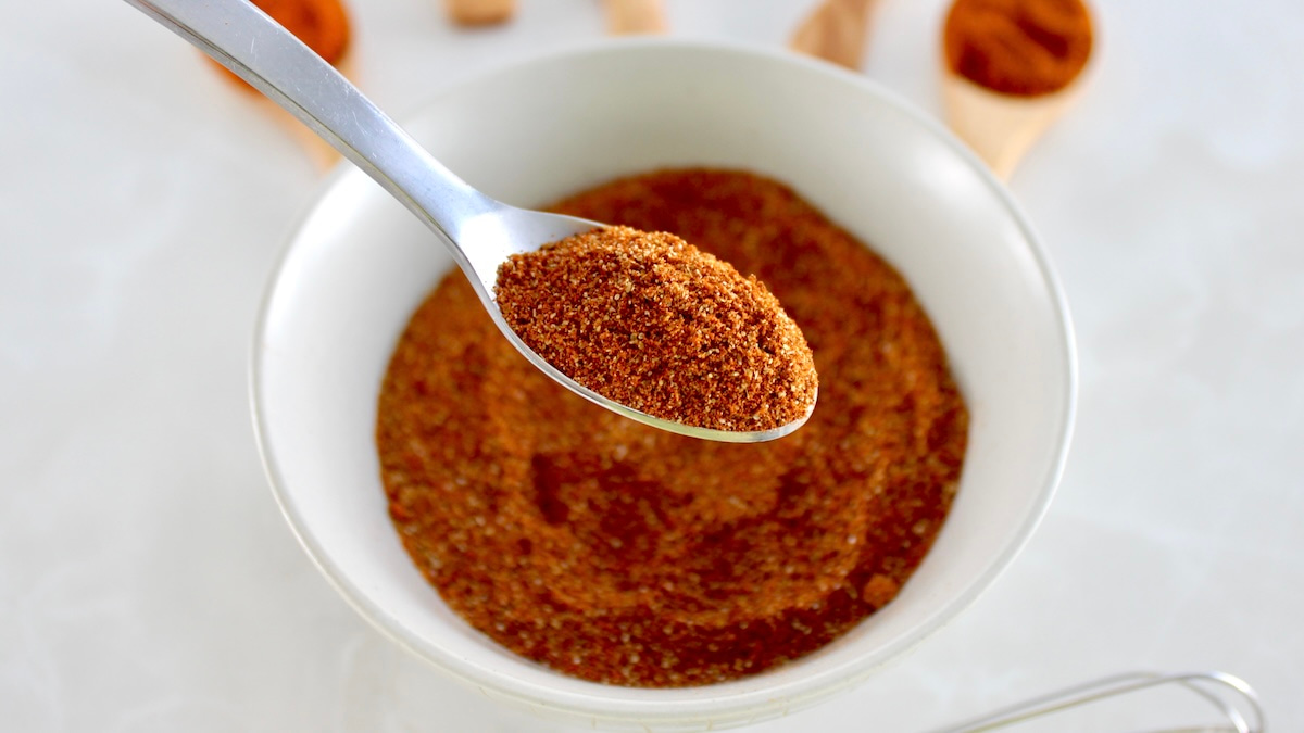 closeup of spoon holding up Homemade Chili Seasoning over white bowl