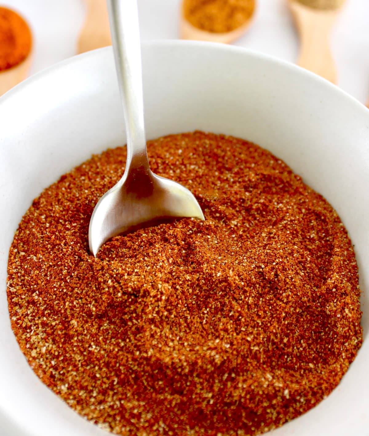 closeup of Homemade Chili Seasoning in white bowl with silver spoon