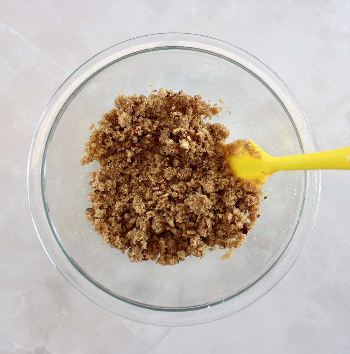 Keto Blackberry Crumble topping in glass bowl with yellow spoon on side