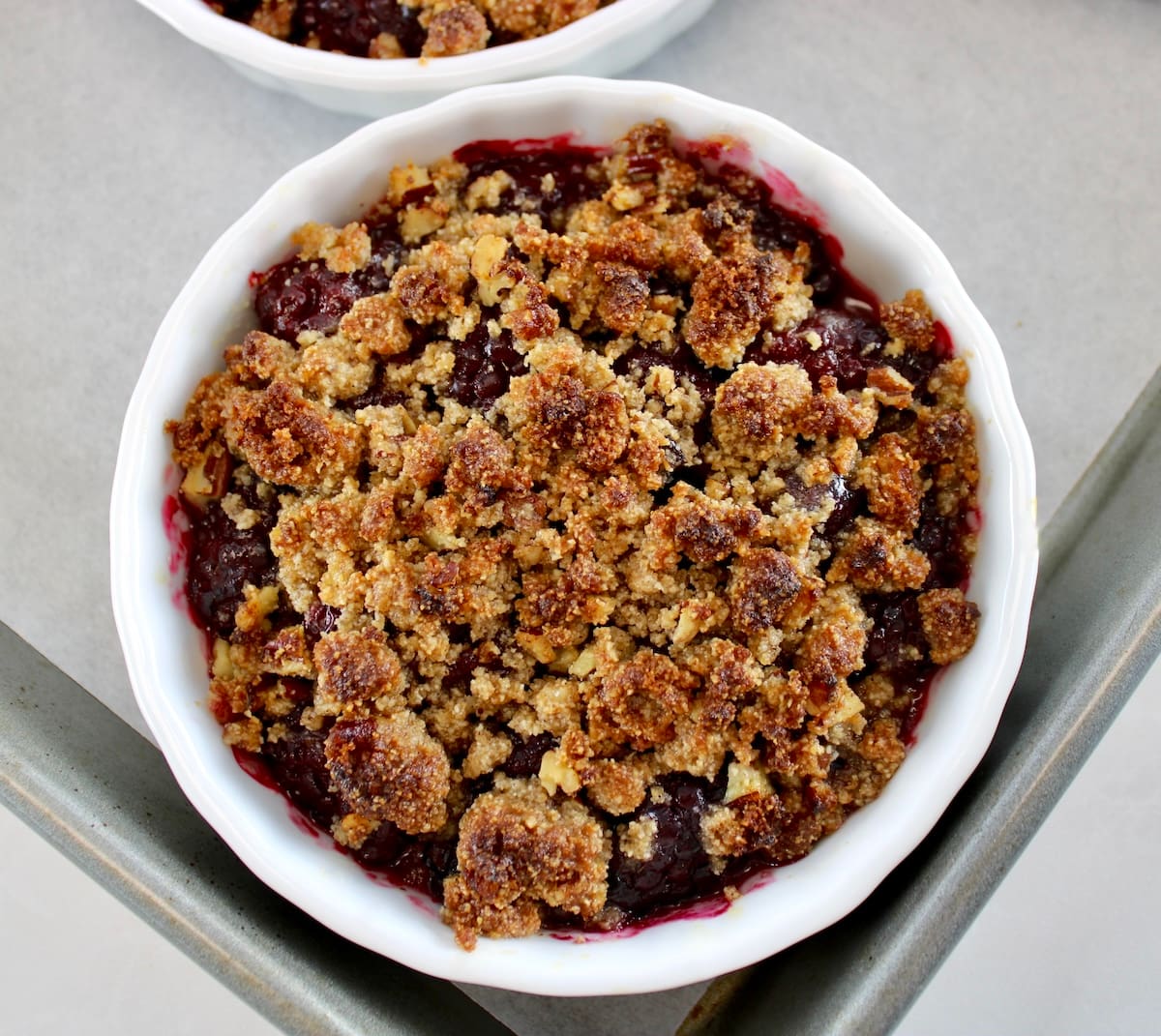 Keto Blackberry Crumble in white ramekin on baking sheet