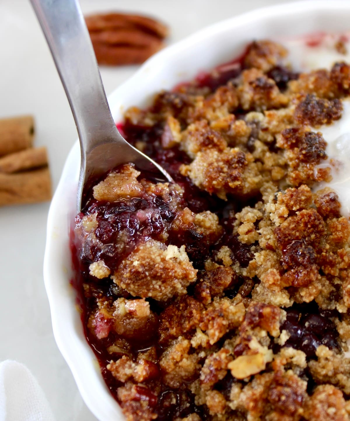 spoon scooping Keto Blackberry Crumble in white ramekin