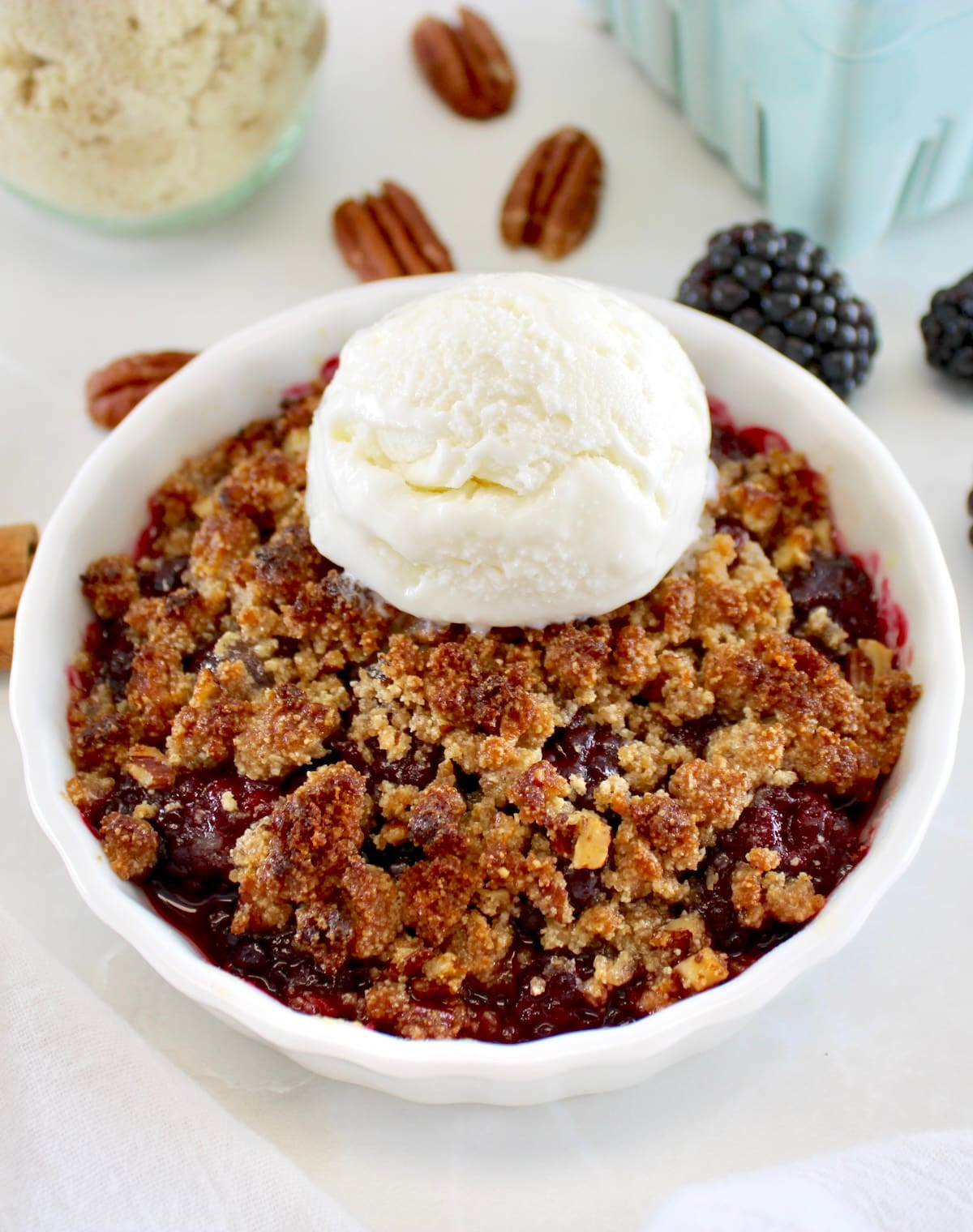 closeup of Keto Blackberry Crumble in white ramekin with vanilla ice cream