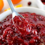 Keto Cranberry Sauce in spoon hold up over white bowl