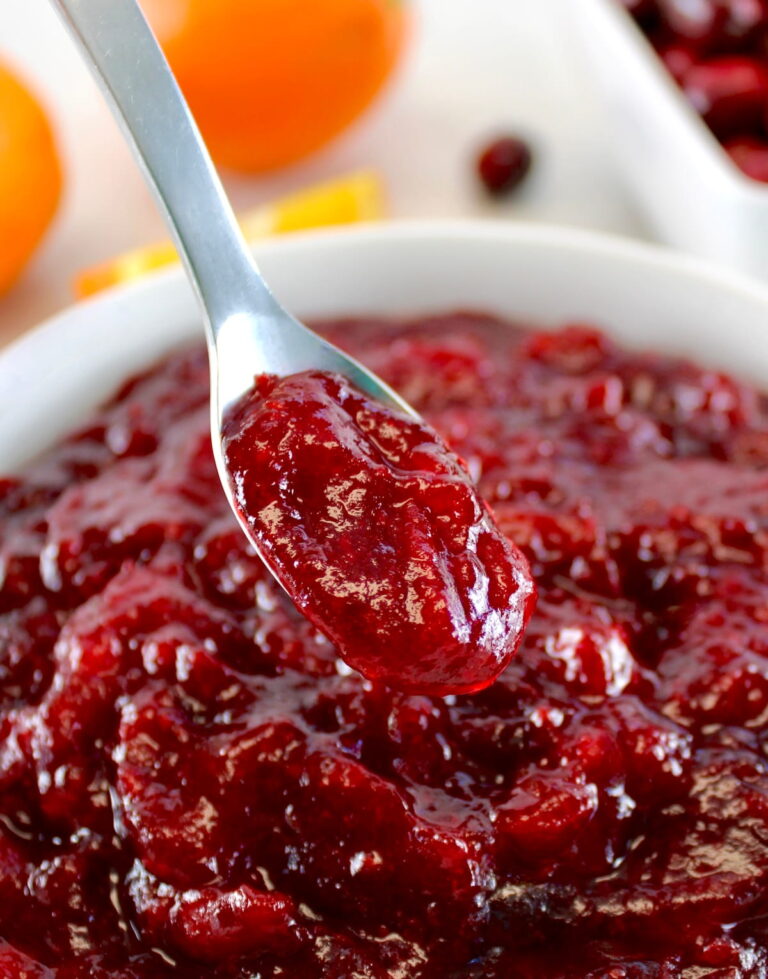 Keto Cranberry Sauce in spoon hold up over white bowl