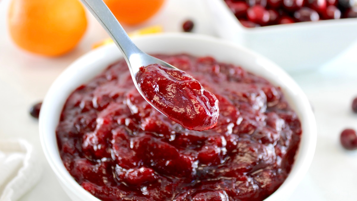 Keto Cranberry Sauce in spoon held over white bowl