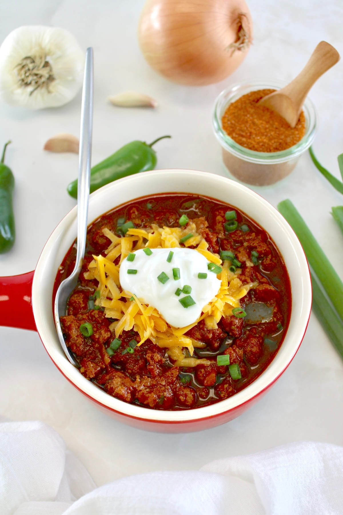 overhead view of Keto Instant Pot No-Bean Chili in crock with shredded cheddar and sour cream on top