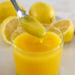 Keto Lemon Curd dripping off spoon into open glass jar