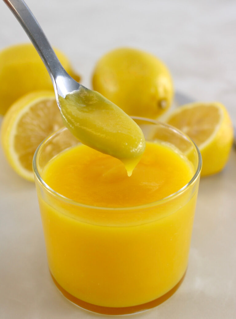 Keto Lemon Curd dripping off spoon into open glass jar