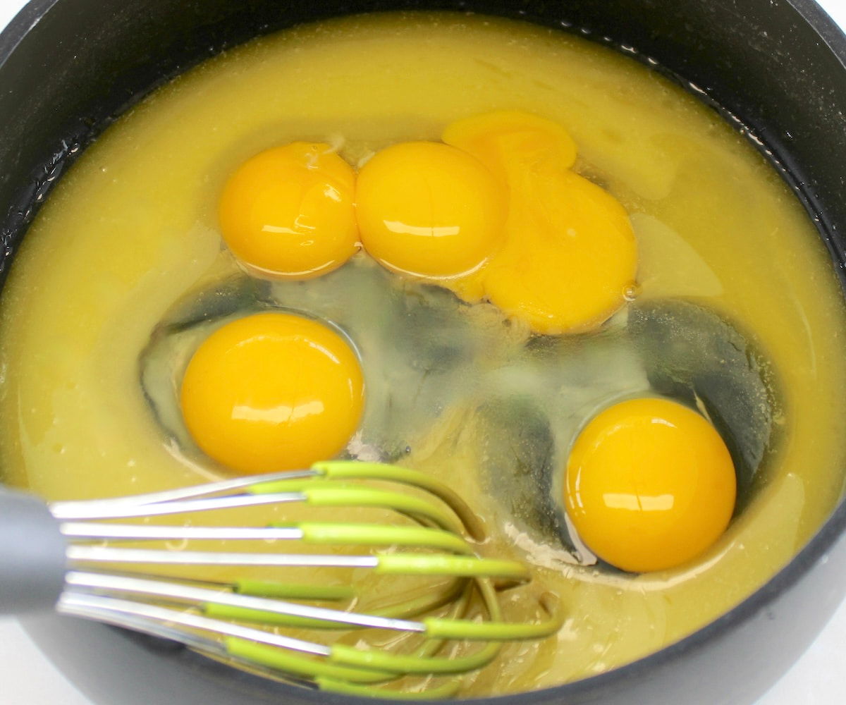 eggs in saucepan with melted butter and whisk