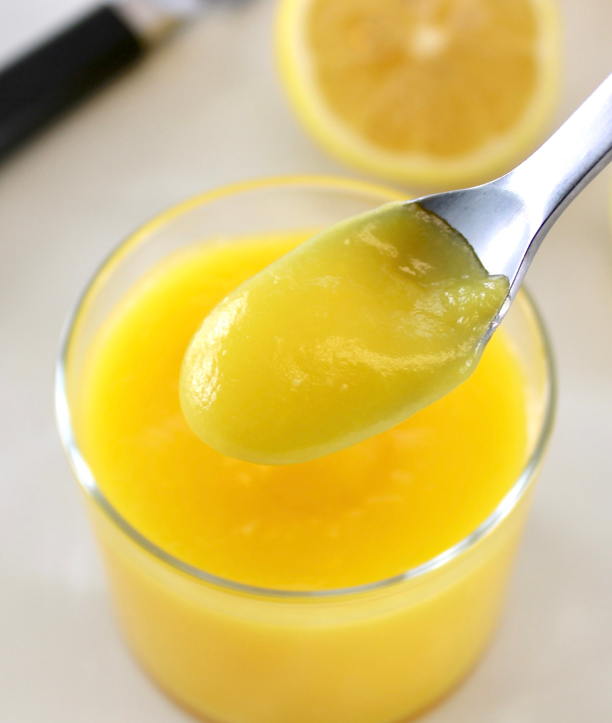 closeup of spoonful of Keto Lemon Curd held over glass jar