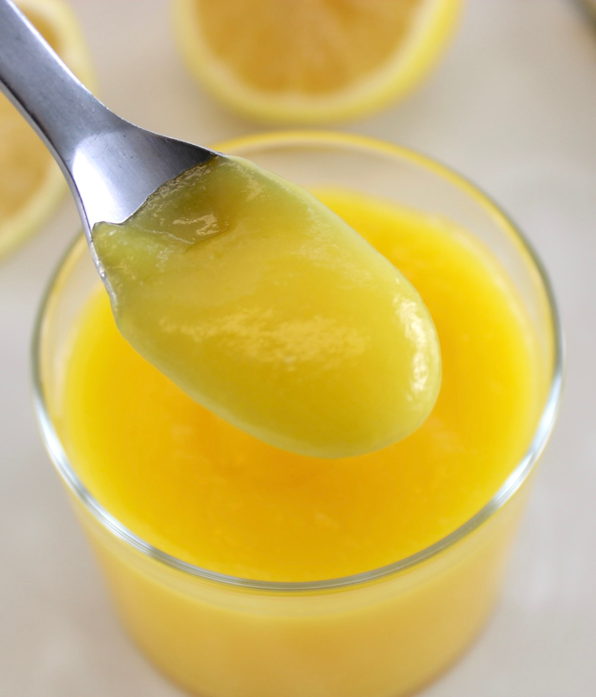holding spoonful of Keto Lemon Curd over open glass jar