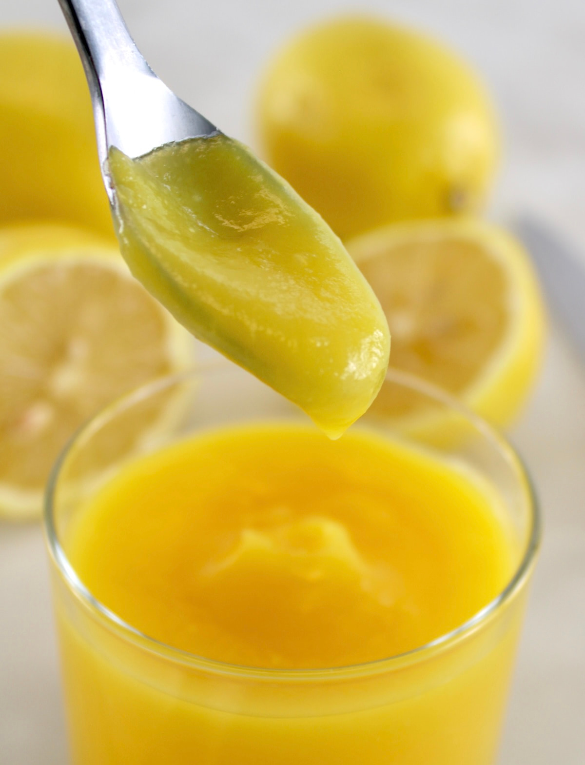 Keto Lemon Curd dripping off spoon into open glass jar