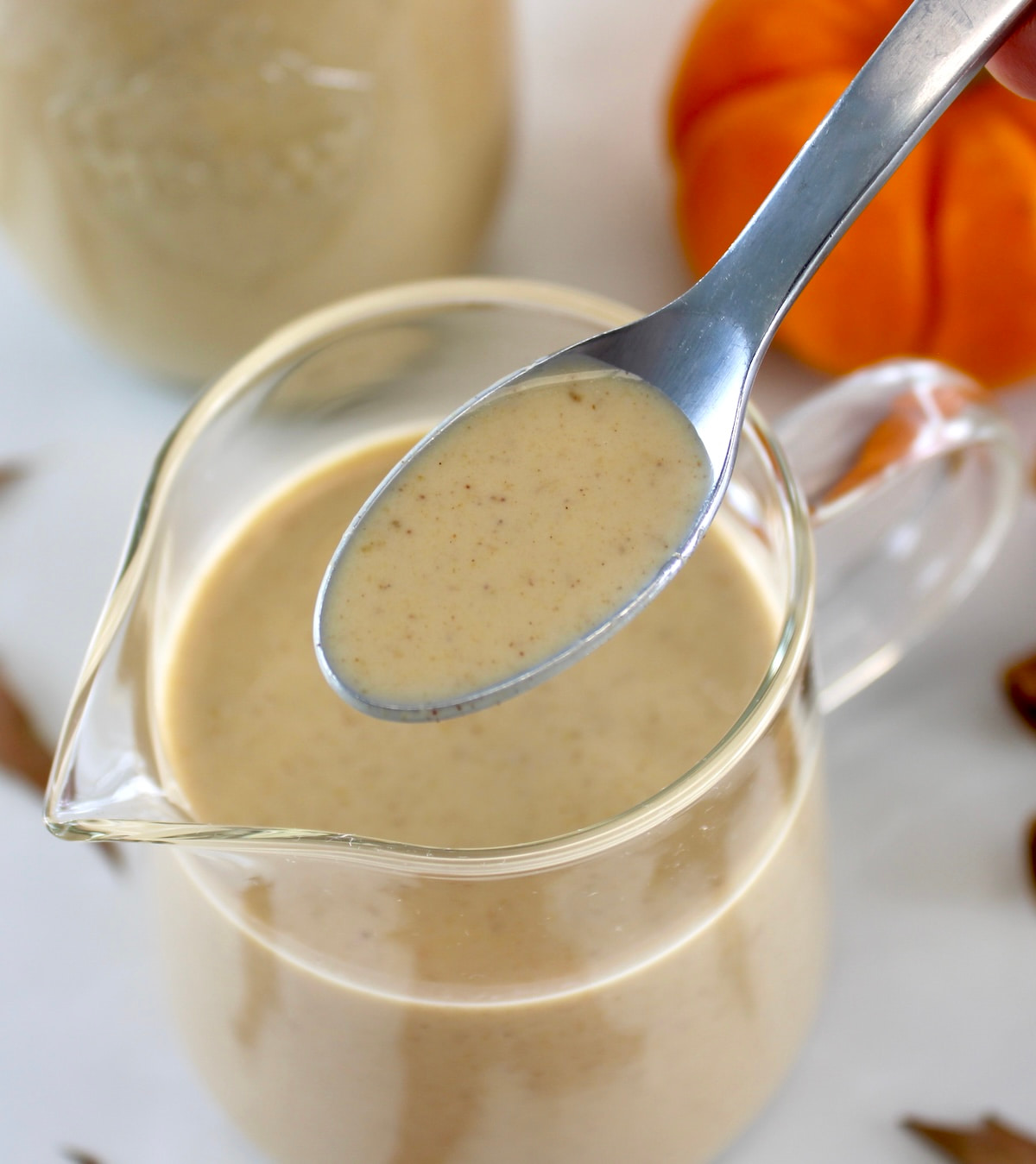 spooning out Keto Pumpkin Spice Coffee Creamer of glass pitcher