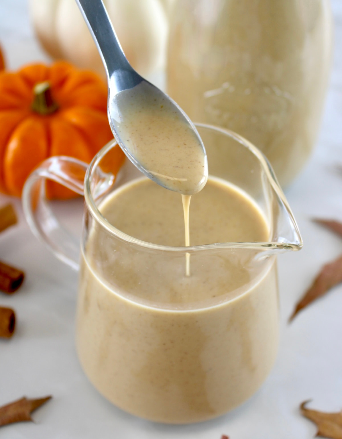 Keto Pumpkin Spice Coffee Creamer dripping off spoon into glass pitcher