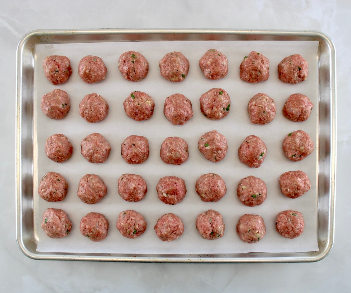 35 raw Keto Swedish Meatballs on parchment lined baking sheet