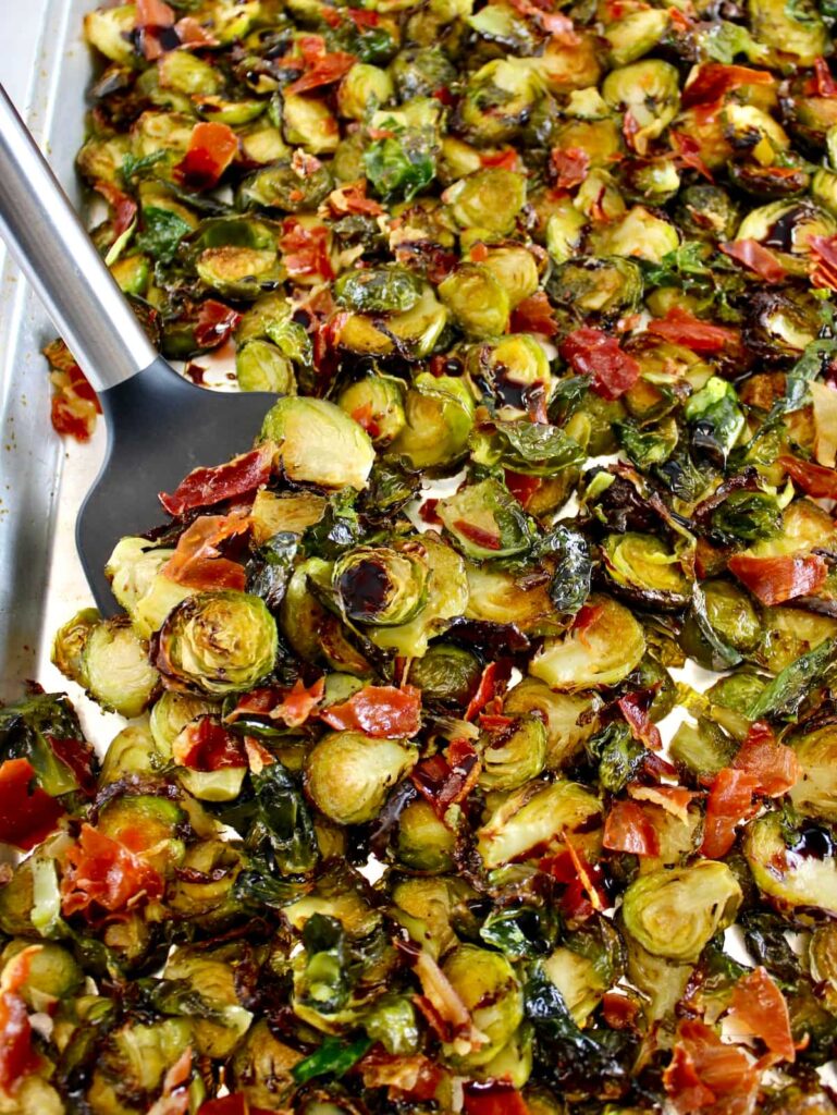 Roasted Balsamic Brussels Sprouts with Prosciutto on baking sheet with spatula